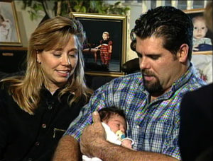 Nancy watches as her husband cradles their baby during 