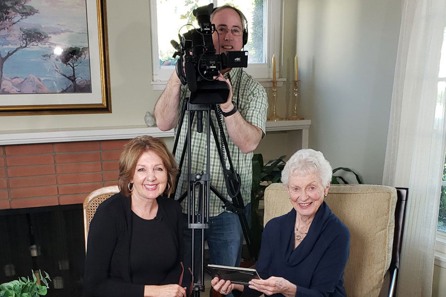 Jane poses with Ann and cameraman Dan during a video interview in her home.